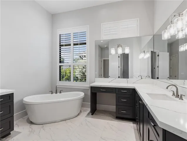 Bathroom with vanity, a freestanding bath, and light marble finish flooring