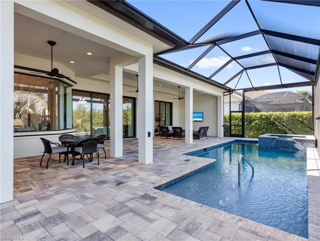 View of pool with outdoor dining space, a sunroom, a patio, a pool with connected hot tub, and a lanai