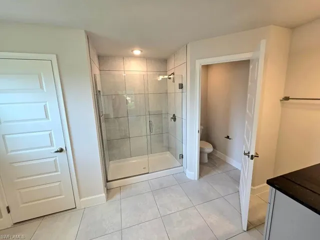 Bathroom featuring vanity, tile patterned floors, toilet, and an enclosed shower