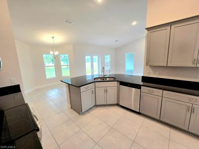 Kitchen featuring dishwasher, kitchen peninsula, sink, range, and gray cabinets