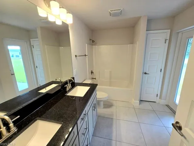 Full bathroom with toilet, vanity,  shower combination, and tile patterned flooring
