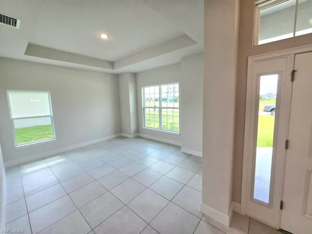 Foyer with light tile patterned flooring and a raised ceiling