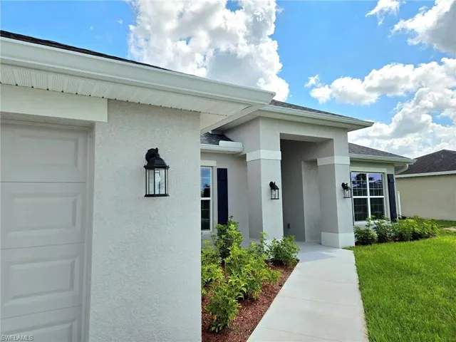 Doorway to property with a lawn and a garage
