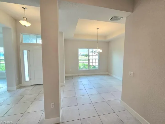 Tiled entryway featuring an inviting chandelier and a raised ceiling