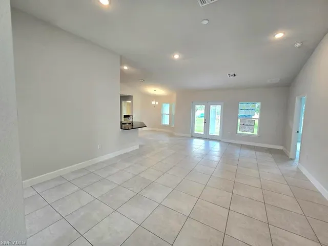 Tiled spare room featuring lofted ceiling and an inviting chandelier