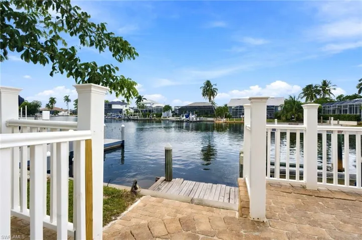 Waterfront property featuring a stone-paved patio, white composite railing, and a private wooden dock