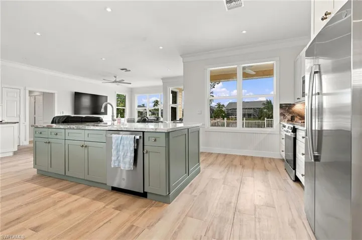 Kitchen featuring a large center island with stone countertop, wood-finish flooring, stainless steel appliances, recessed ceiling lighting, and crown molding