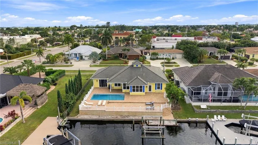 Waterfront residence featuring a private swimming pool, paved patio, perimeter fencing, and a built-in boat dock