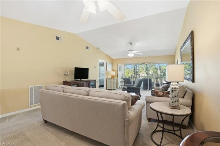 Living room with carpet, lofted ceiling, and ceiling fan