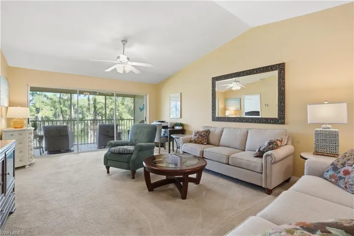 Living area with vaulted ceiling, light colored carpet, and a ceiling fan