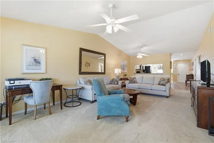 Living room with light carpet, lofted ceiling, and ceiling fan