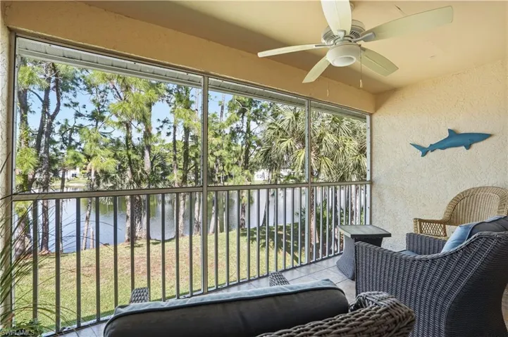 Sunroom with a water view, a balcony, and a ceiling fan