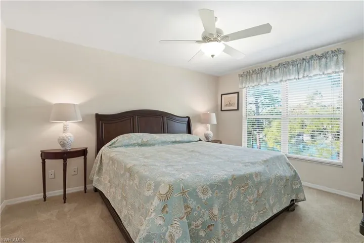 Carpeted bedroom with ceiling fan and baseboards