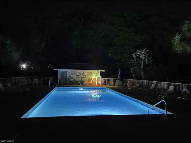 Pool at night with an outdoor structure and a community pool