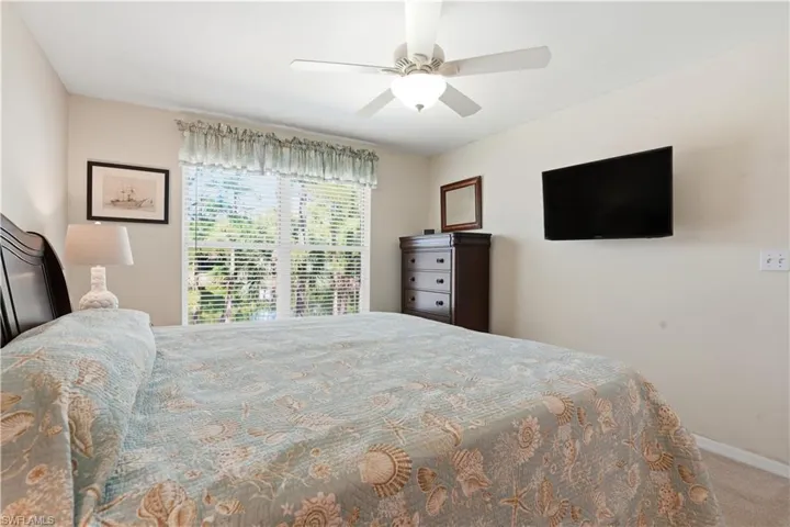 Bedroom with light carpet, ceiling fan, and ensuite bath
