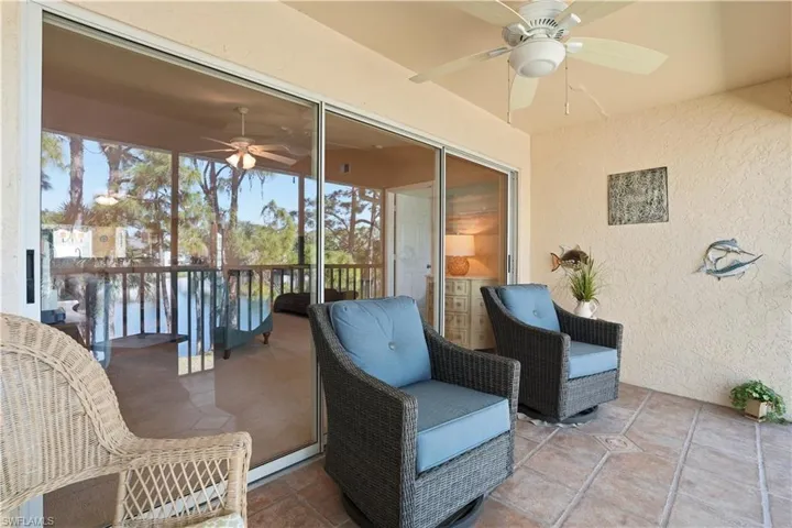 Sunroom with a water view, a ceiling fan, and a balcony