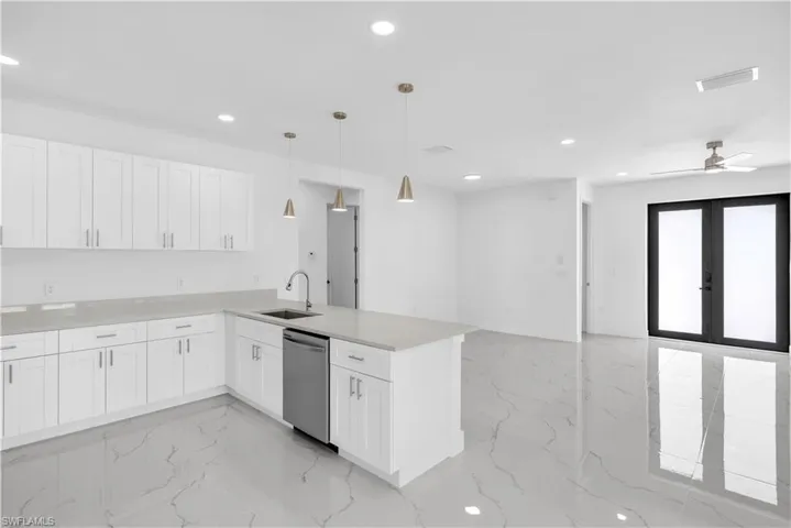 Kitchen featuring white cabinets, a peninsula, stainless steel dishwasher, and ceiling fan