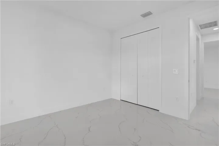 Unfurnished bedroom with light marble finish floors and a closet