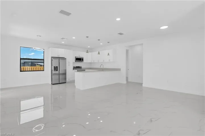 Kitchen with white cabinets, open floor plan, stainless steel appliances, a peninsula, and light countertops