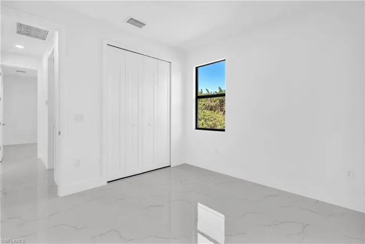 Unfurnished bedroom with a closet and light marble finish flooring