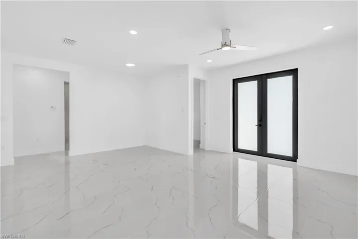 Empty room with french doors, a ceiling fan, recessed lighting, and light marble finish floors