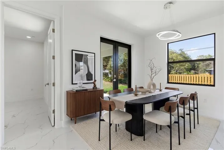 Dining room featuring light marble finish floors and french doors