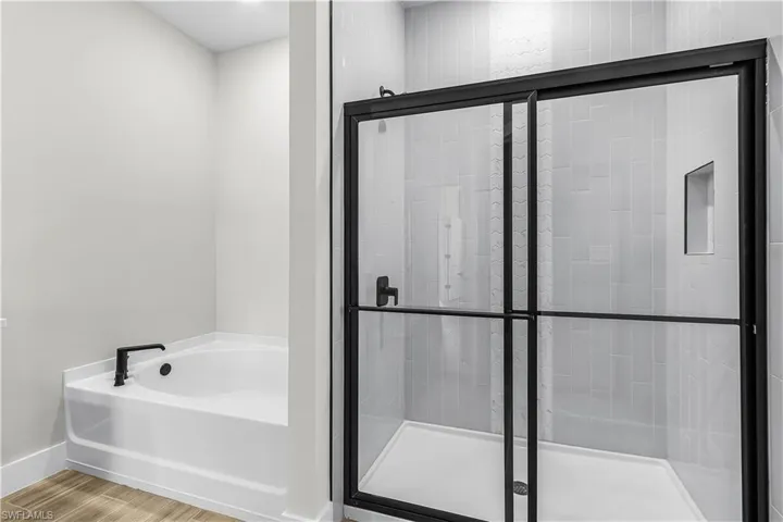 Bathroom with a garden tub, a shower stall, and wood finished floors