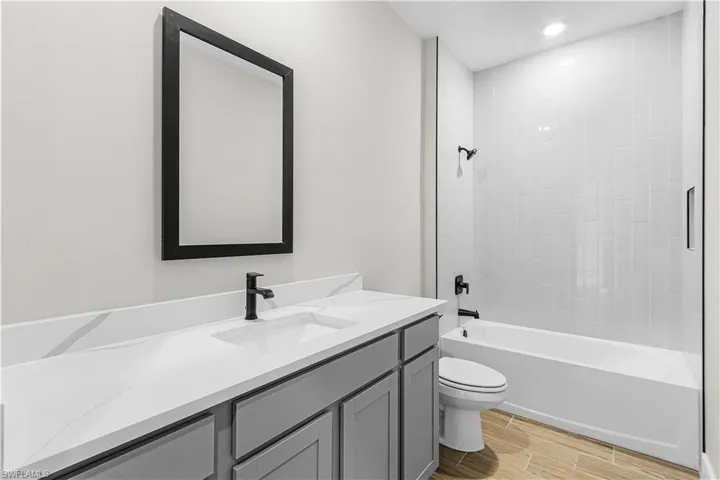 Bathroom featuring wood tiled floors, vanity,  shower combination, and recessed lighting