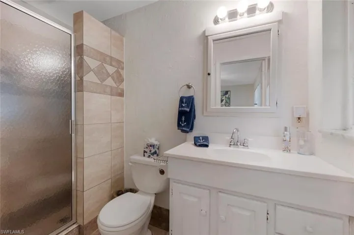 Bathroom featuring vanity, walk in shower, and toilet