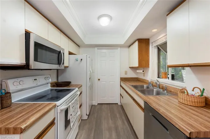 Kitchen featuring white cabinetry, a tray ceiling, sink, light hardwood / wood-style floors, and appliances with stainless steel finishes