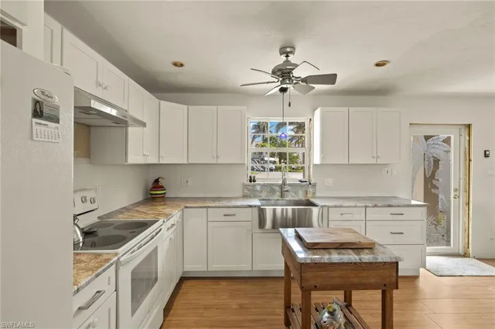Kitchen with white cabinetry, light hardwood / wood-style floors, sink, white appliances, and ceiling fan