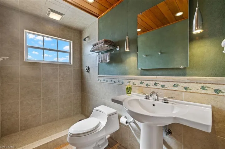 Bathroom featuring tile walls, toilet, and a tile shower