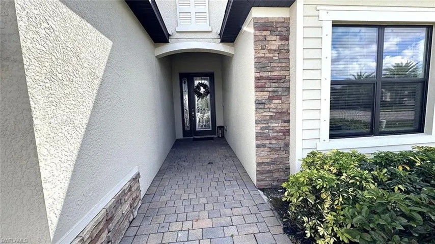 Doorway to property with stone siding and stucco siding