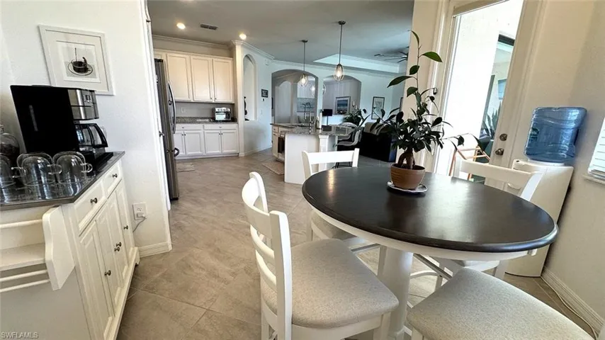 Dining space featuring arched walkways, crown molding, light tile patterned floors, and recessed lighting