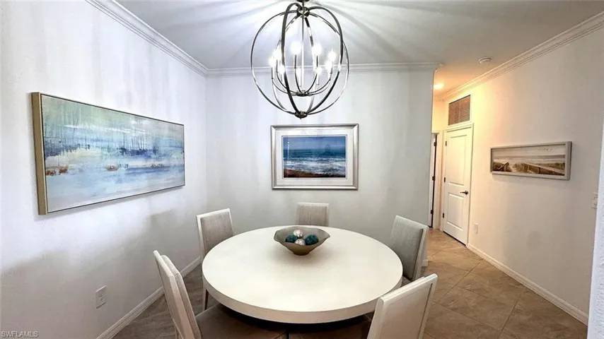 Tiled dining space with ornamental molding and a chandelier