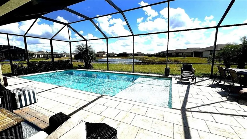 Swimming pool with a residential view, a water view, a yard, a sunroom, and glass enclosure