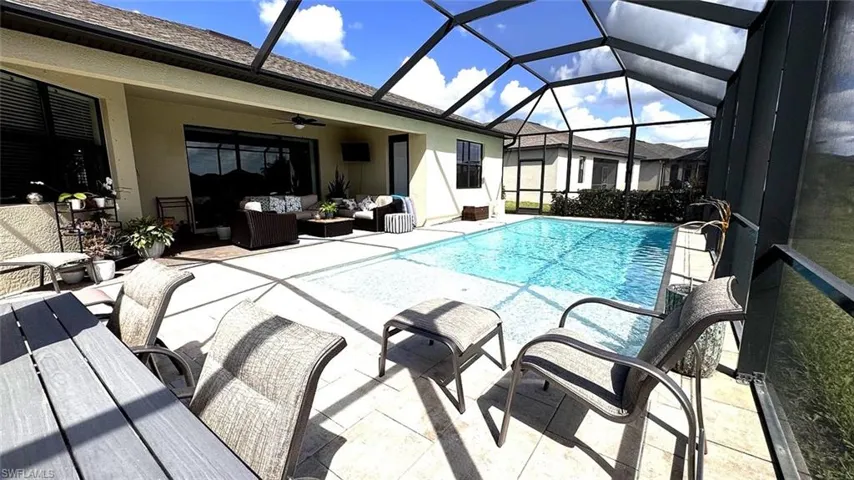 Outdoor pool featuring an outdoor living space, a sunroom, a patio area, and a lanai