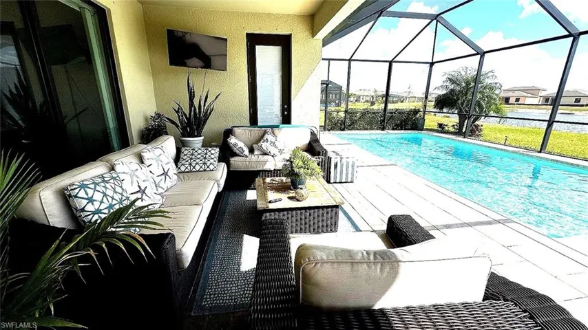 Swimming pool featuring an outdoor hangout area, a sunroom, a patio area, and glass enclosure