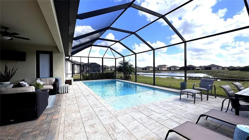 Swimming pool with an outdoor hangout area, a sunroom, a water view, a residential view, and glass enclosure
