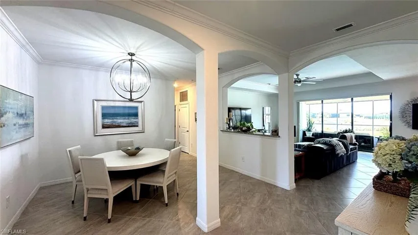 Dining space with arched walkways, ornamental molding, a chandelier, and a ceiling fan