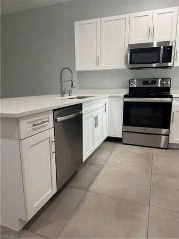 Kitchen with stove, white cabinetry, and stainless steel dishwasher