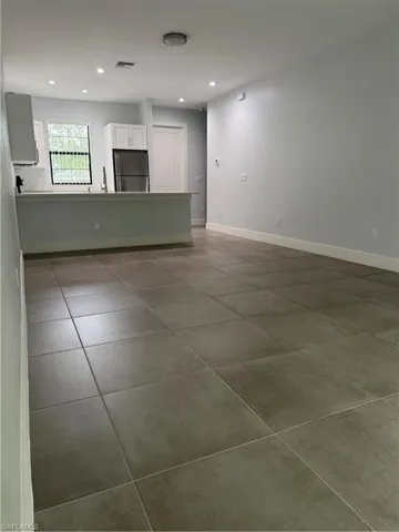 Unfurnished living room featuring recessed lighting and dark tile patterned floors