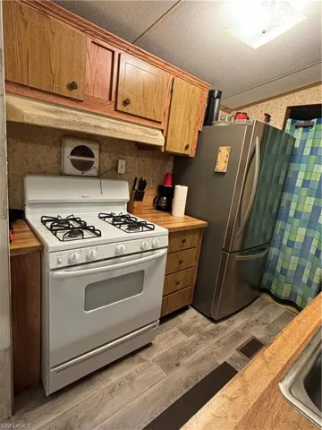 Kitchen featuring fridge, sink, white range oven, and light wood-type flooring