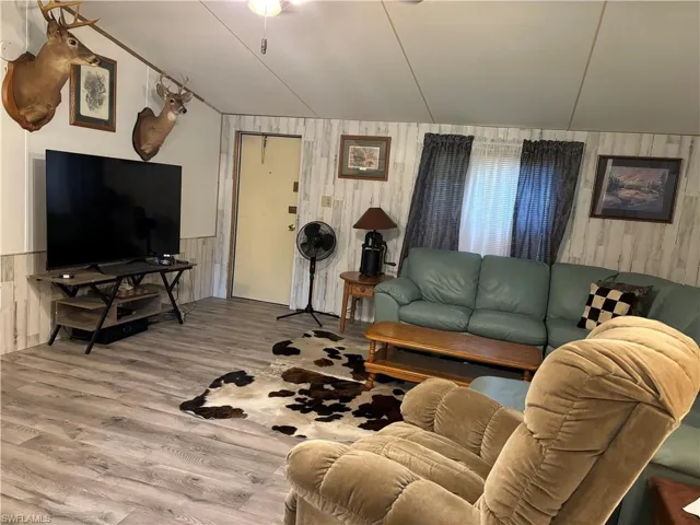 Living room featuring lofted ceiling, wood-type flooring, and wood walls