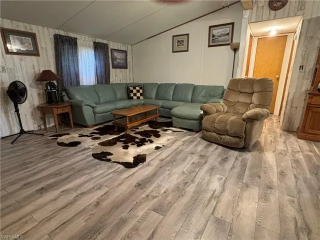 Living room with lofted ceiling and light hardwood / wood-style floors