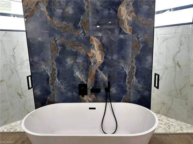 Bathroom with shower with separate bathtub, tile walls, and hardwood / wood-style flooring