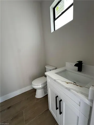 Bathroom with hardwood / wood-style flooring, vanity, and toilet
