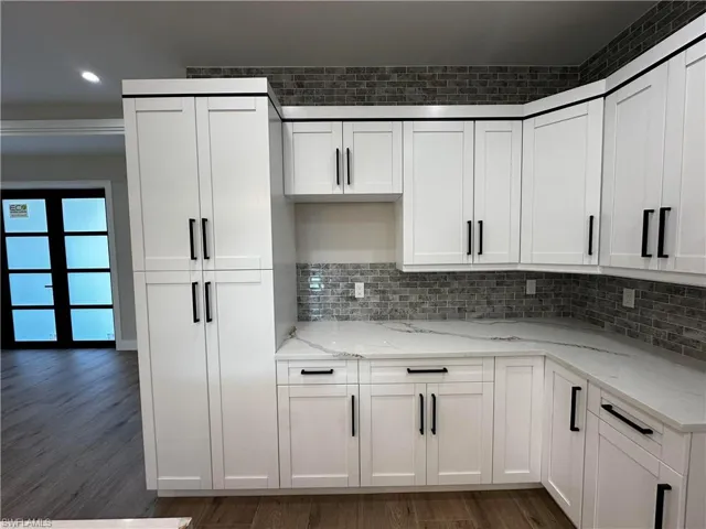 Kitchen with light stone countertops, dark hardwood / wood-style flooring, and white cabinets