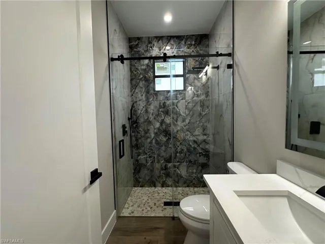 Bathroom featuring walk in shower, wood-type flooring, vanity, and toilet