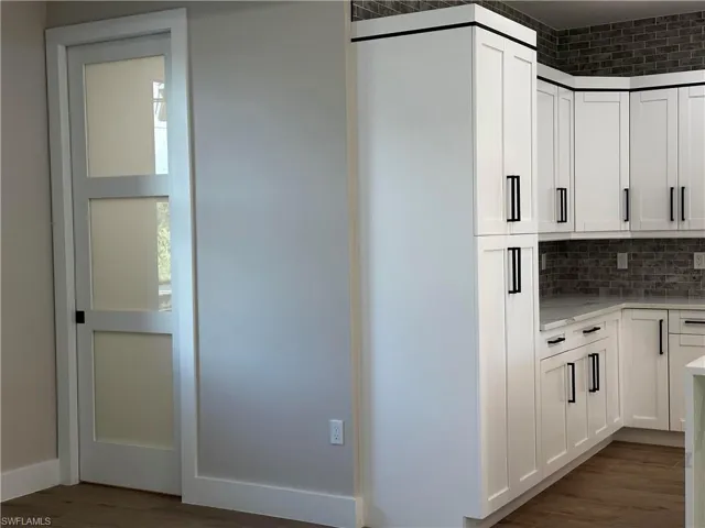 Kitchen featuring backsplash, white cabinetry, and dark hardwood / wood-style flooring